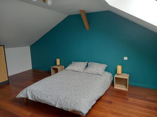 une chambre avec un lit avec un mur bleu dans l'établissement Le Murger, sud Bourgogne, à Ozenay