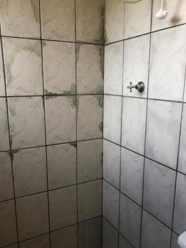 a bathroom with a tiled shower with a faucet at Camping beira mar in Bertioga