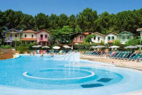 une piscine dans un complexe hôtelier avec chaises et parasols dans l'établissement Appart moderne grande piscine Lacanau océan pinède, à Lacanau