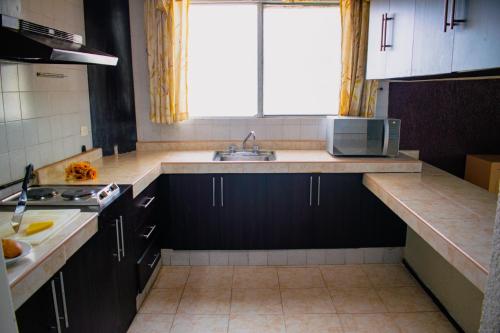 a kitchen with black cabinets and a sink and a window at Suites del Sol Hotel & Apartments in Mérida