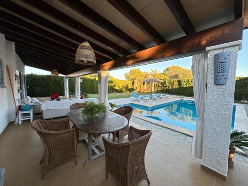 een patio met een tafel en stoelen en een zwembad bij sa rapita paradise in Sa Ràpita