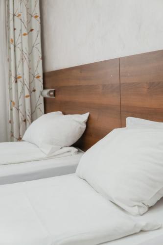two beds with white pillows and a wooden headboard at Hotel Damis in Pale