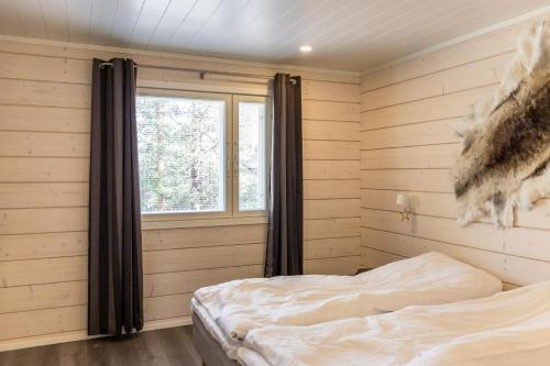 a bedroom with a bed in a room with wooden walls at Holy Moly by Hilla Villas in Pelkosenniemi