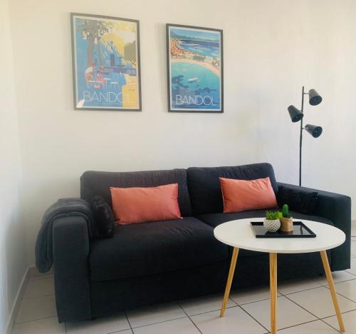 een woonkamer met een zwarte bank en een tafel bij Studio climatisé 4 couchages centre Bandol et Plage in Bandol