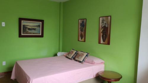 a bedroom with green walls and a bed with pink sheets at Apartamento na Praia de Copacabana in Rio de Janeiro