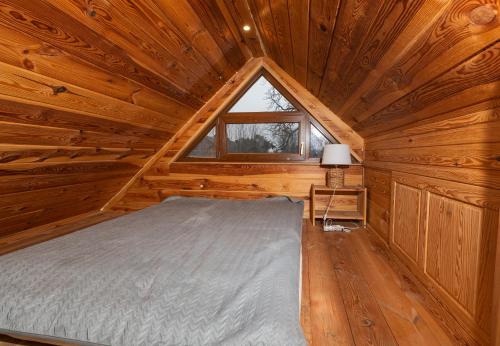 a bedroom with a bed in a wooden cabin at Poleskie zacisze, domek Bocian, kominek, balia,sauna,wifi in Helenin