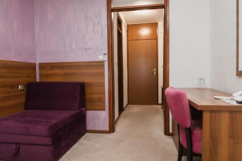 a room with a purple couch and a desk and a table at Hotel Damis in Pale