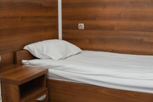 a bed with a pillow and a wooden headboard at Hotel Damis in Pale