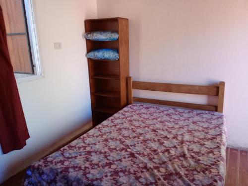Dormitorio pequeño con cama y estante de libros en Monoambiente villa Gesell en Villa Gesell