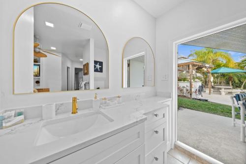 een witte badkamer met 2 wastafels en een grote spiegel bij Skipper's Landing - 4 Bedroom with Heated Pool in Cocoa Beach