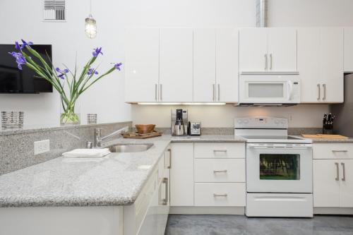 a kitchen with white appliances and purple flowers in a vase at Petaluma Warehouse Lofts Unit C in Petaluma