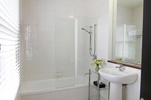 a white bathroom with a sink and a shower at Hanmer Springs Hotel in Hanmer Springs