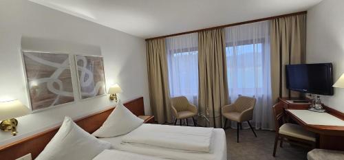 a hotel room with a bed and a desk and a television at Hotel Garni Vierjahreszeiten in Bad Staffelstein