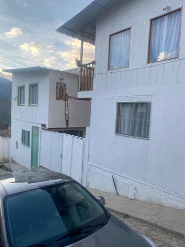 a car parked in front of a white house at GLL HOTEL in El Cocuy