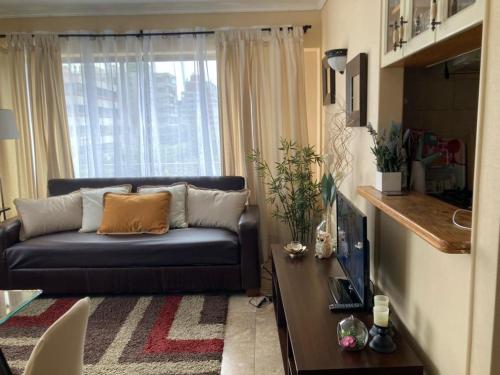 a living room with a couch and a window at Acogedor Departamento amoblado Viña del Mar Poniente 2D 1B in Viña del Mar