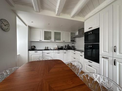 une cuisine avec des placards blancs et une table en bois avec des chaises dans l'établissement Domaine du Deven Grandvaux, à Grandvaux