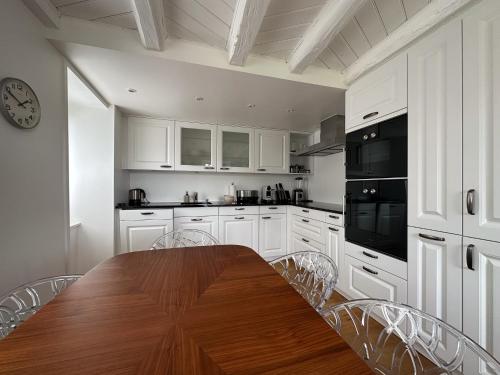 a kitchen with white cabinets and a wooden table with chairs at Domaine du Deven Grandvaux in Grandvaux