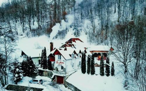 ein schneebedecktes Haus mit einem Auto davor in der Unterkunft La Mama in Pietroasa