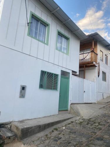 biały budynek z zielonymi drzwiami i balkonem w obiekcie GLL HOTEL w mieście El Cocuy
