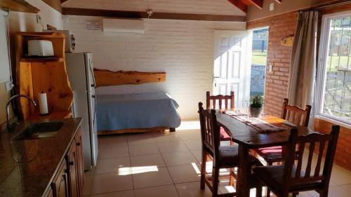 uma cozinha e sala de jantar com uma mesa e uma cama em Cabañas La Delfina em Potrero de los Funes