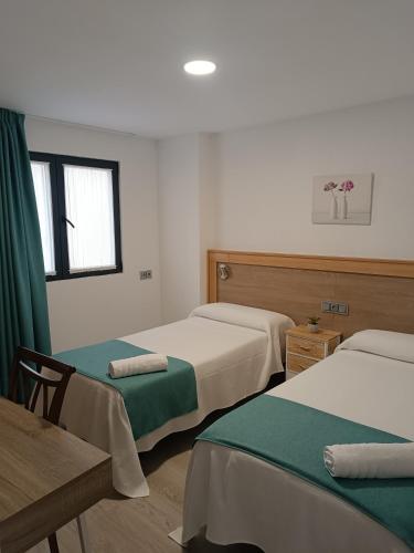 a room with three beds and a table and a window at Apartamentos turisticos Ávila Puerta de San Isidro 1-4 in Avila