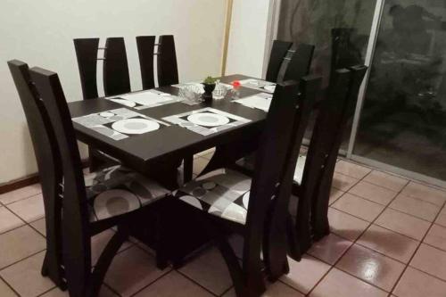 una mesa de comedor negra con sillas negras, una mesa negra y un sillón en Dulce Hogar 01, en Loja