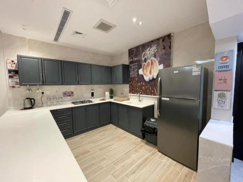 a kitchen with black cabinets and a stainless steel refrigerator at شاليه رحال in Yanbu Al Bahr