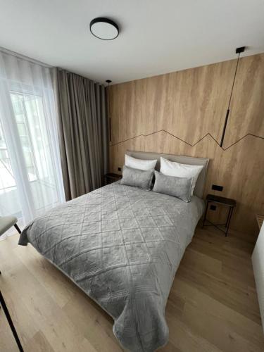 a bedroom with a large bed with a wooden wall at Mountains & SPA Apartament Zakopiański in Zakopane