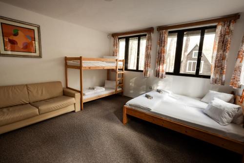 a bedroom with two beds and a couch and a bunk bed at Penzion a Restaurace Kamínek in Doksy