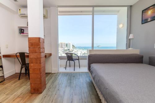 1 dormitorio con cama, escritorio y ventana grande en Apartamento Barra Beach, en Río de Janeiro