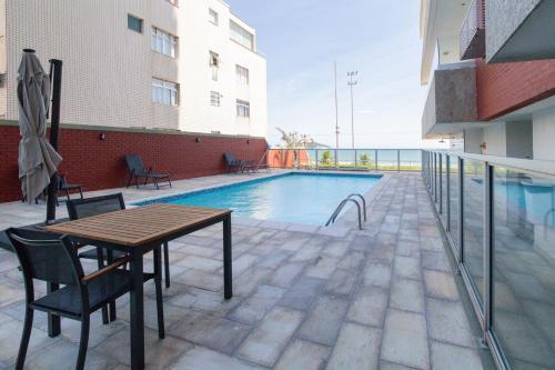 un patio con mesa y sillas junto a una piscina en Apartamento Barra Beach, en Río de Janeiro