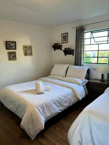 1 Schlafzimmer mit 2 Betten mit weißer Bettwäsche und einem Fenster in der Unterkunft Habitación Privada en Mongui in Monguí