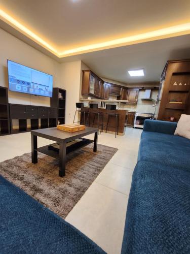 uma sala de estar com um sofá azul e uma mesa em Dair Ghbar - Amman Apartment em Amã