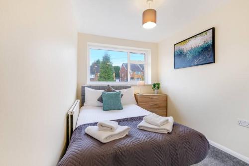 a bedroom with a bed with two towels on it at 4 Bedroom High Wycombe Home With Free Parking Free WiFi Private Garden - Great Transport Links! in Buckinghamshire