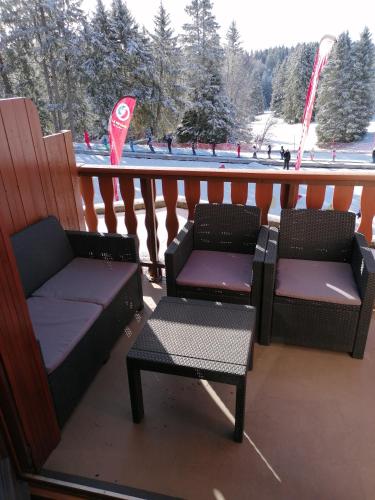 two chairs and a table on a balcony with a snow covered slope at Appartement 5 personnes en station Savoie Grand Revard in Trévignin