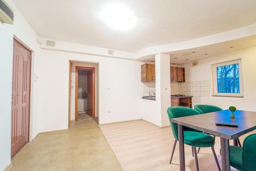 a kitchen and dining room with a table and green chairs at Hera's Bohemian Home in Arad