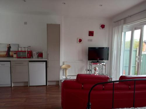 a living room with a red couch and a kitchen at Colchester Town, modern, detached, guest house in Colchester