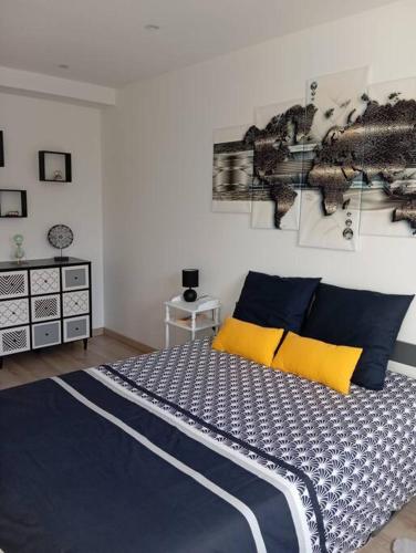 Schlafzimmer mit einem Bett mit blauen und gelben Kissen in der Unterkunft Appartement Cosy avec Jardin in Vaux-sur-Seine