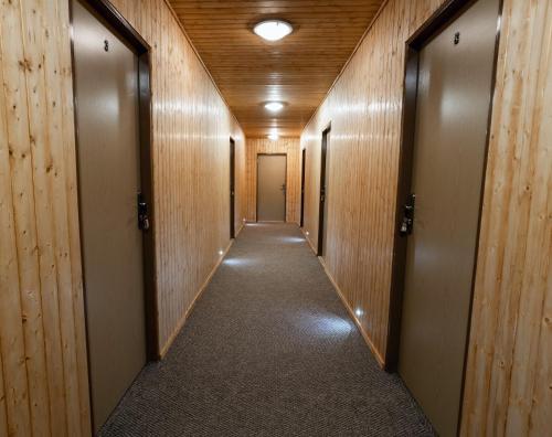 a corridor of a hallway with wooden walls and doors at Penzion a Restaurace Kamínek in Doksy