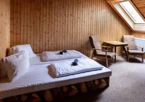 a bedroom with two beds and two chairs and a window at Penzion a Restaurace Kamínek in Doksy