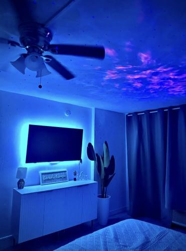 Habitación azul con TV y ventilador de techo. en OCEAN VIEW Condo Daytona Beach, en Daytona Beach