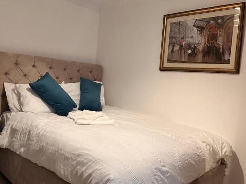 un letto con cuscini blu e una foto sul muro di One small bed apartment by monishortlets a Dagenham