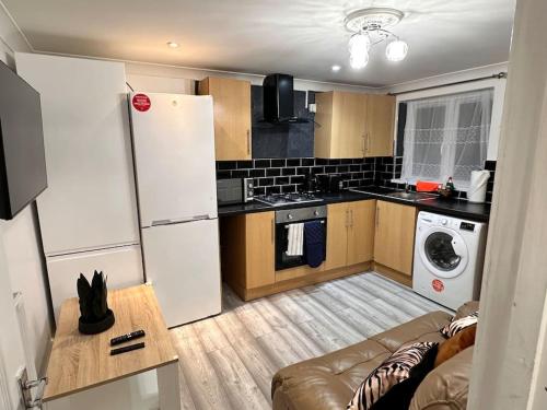 a small kitchen with a couch and a refrigerator at One small bed apartment by monishortlets in Dagenham