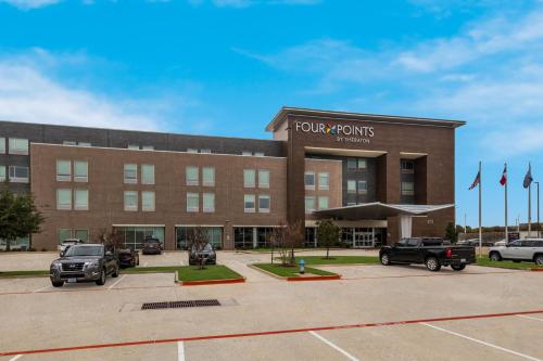 a large brick building with cars parked in a parking lot at Four Points by Sheraton Plano in Plano