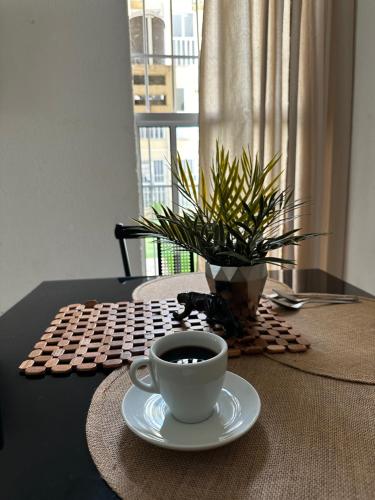 a cup of coffee on a table with a plant at Apartamento inteiro Varzea Grande MT in Várzea Grande