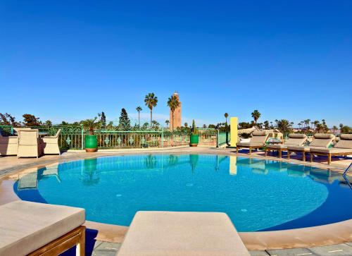 a large swimming pool with lounge chairs and palm trees at Sillage Palace Sky & Spa in Marrakech