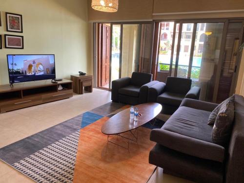 a living room with a couch and a tv at one bedroom apartments aqaba on 2 swimming pool Tala bay in Aqaba
