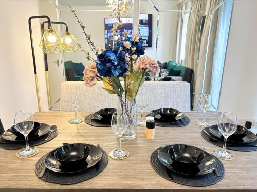 a table with plates and glasses and a vase of flowers at Luxury London Two Bedroom Apartment in West Dulwich