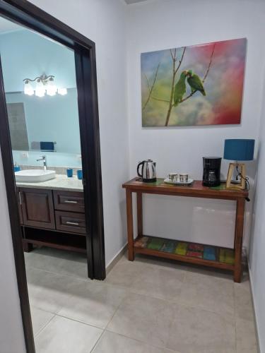 a bathroom with a sink and a bird painting on the wall at vista de loros in Sámara