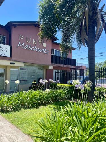 a building with a palm tree in front of it at Punto Maschwitz Alquileres - Departamento dos ambientes in Ingeniero Maschwitz